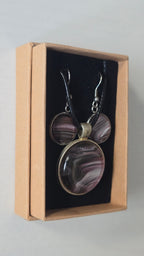 Rundes Cabochon-Schmuckset mit Anhänger und Ohrringen, abstrakt gemustert in Violett, Mauve, Schwarz und silbrig schimmernden Nuancen.