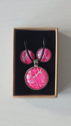 Rundes Cabochon-Schmuckset mit Anhänger und Ohrringen an schwarzem Band, mit organischem Muster in Fuchsia, Himbeerrosa und Pink sowie feinen hellen Linien.