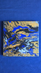 Zwei quadratische abstrakte Acryl-Leinwandbilder mit fliessenden Strukturen in kräftigem Blau, Gold, Weiss, Grau und Schwarz.