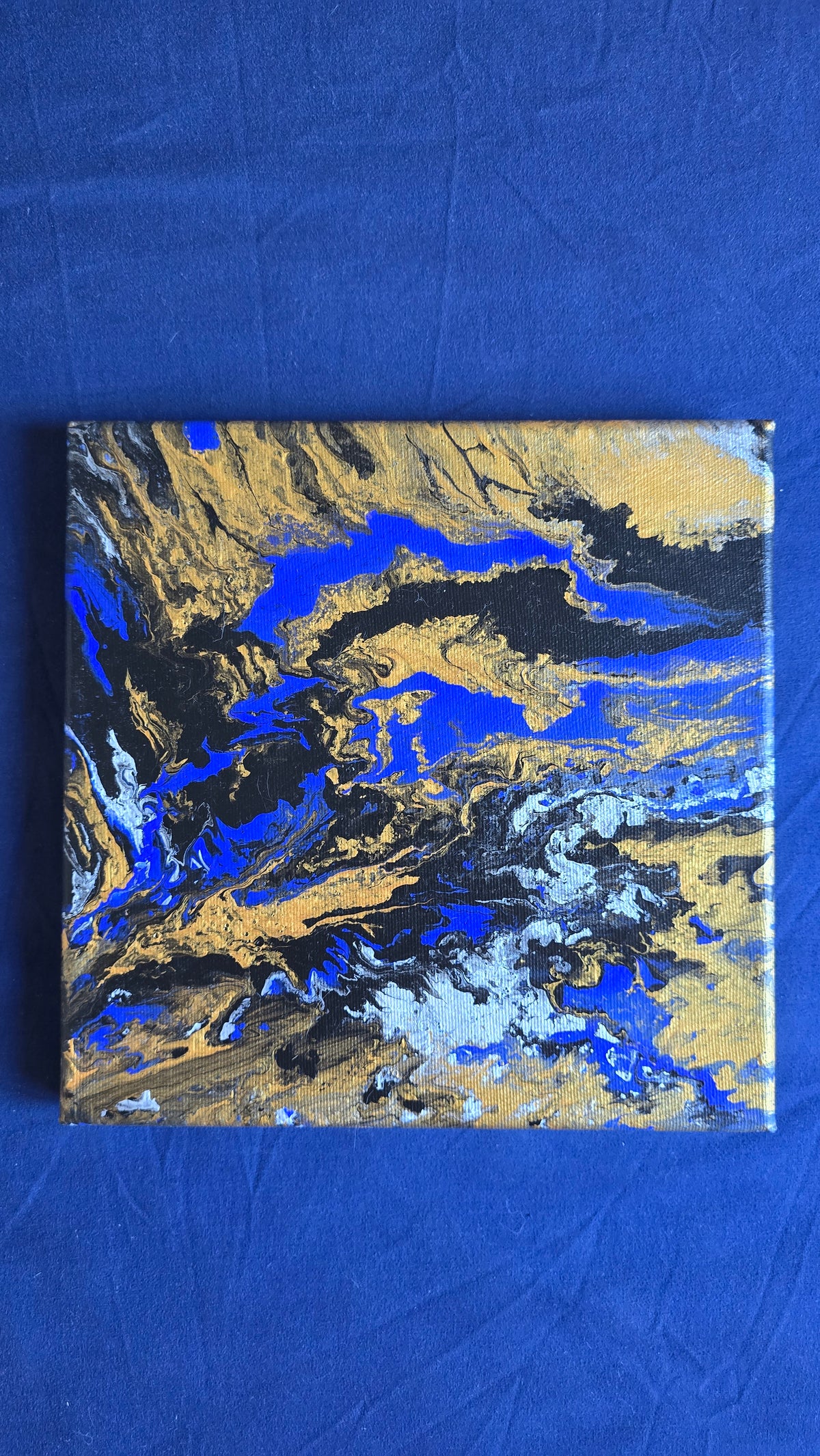 Zwei quadratische abstrakte Acryl-Leinwandbilder mit fliessenden Strukturen in kräftigem Blau, Gold, Weiss, Grau und Schwarz.