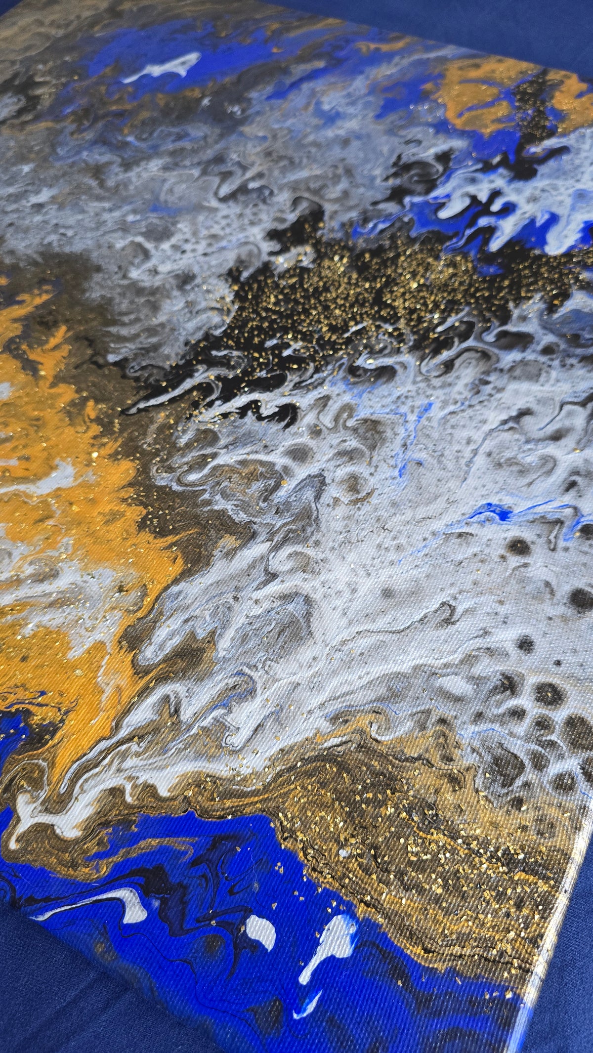 Zwei quadratische abstrakte Acryl-Leinwandbilder mit fliessenden Strukturen in kräftigem Blau, Gold, Weiss, Grau und Schwarz.