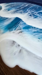 Rundes Resin Wandbild Solas Seafoam auf Holz mit blau-türkisem Meer, weissen Wellen, irisierenden Farbakzenten und sichtbarer Holzstruktur.