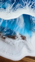 Rundes Resin Wandbild Solas Seafoam auf Holz mit blau-türkisem Meer, weissen Wellen, irisierenden Farbakzenten und sichtbarer Holzstruktur.