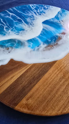 Rundes Resin Wandbild Solas Seafoam auf Holz mit blau-türkisem Meer, weissen Wellen, irisierenden Farbakzenten und sichtbarer Holzstruktur.