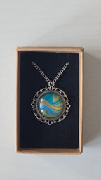 Runde Cabochon Kette Solas Sunlit Current in Türkis, Blau und Gold mit verzierter silberfarbener Fassung und Metallkette.