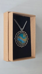 Runde Cabochon Kette Solas Sunlit Current in Türkis, Blau und Gold mit verzierter silberfarbener Fassung und Metallkette.