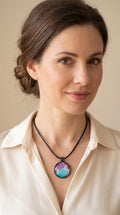 Frau trägt runder Cabochon-Anhänger an schwarzem Band mit verzweigtem, organischem Muster in Türkis, Aqua, Fuchsia, Pink und hellen Linien.