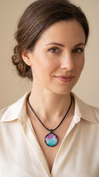 Frau trägt runder Cabochon-Anhänger an schwarzem Band mit verzweigtem, organischem Muster in Türkis, Aqua, Fuchsia, Pink und hellen Linien.