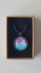 Runder Cabochon-Anhänger an schwarzem Band mit verzweigtem, organischem Muster in Türkis, Aqua, Fuchsia, Pink und hellen Linien.