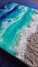 Handgefertigtes Resin-Meeresbild «Solas Turquoise Bay» mit türkisfarbenem Wasser, schäumenden Wellen und natürlichem Kieselstrand auf einem 40 × 40 cm grossen Gesso-Rahmen.