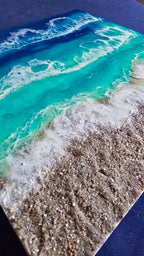 Handgefertigtes Resin-Meeresbild «Solas Turquoise Bay» mit türkisfarbenem Wasser, schäumenden Wellen und natürlichem Kieselstrand auf einem 40 × 40 cm grossen Gesso-Rahmen.