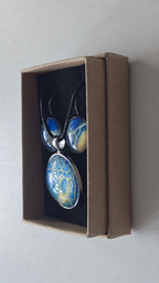 Rundes Cabochon Schmuckset mit schwarzer Kette und zwei Ohrringen, abstrakte Muster in Blau, Türkis, Weiss und Gold mit feinen netzartigen Strukturen.