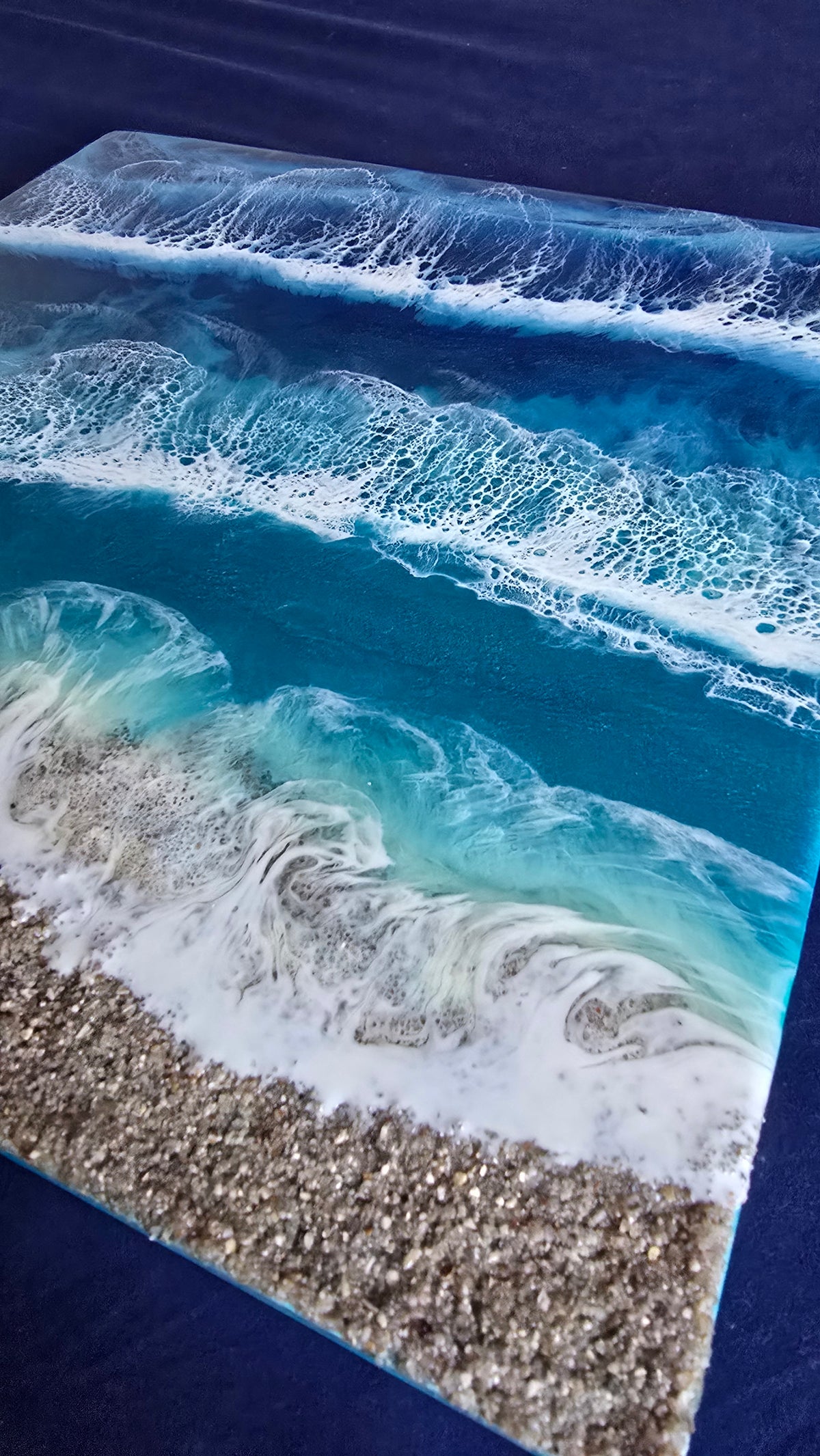 Handgefertigtes Resin-Meeresbild Solas Wild Tide (40 × 40 cm) auf einem strukturierten Gesso-Rahmen mit kraftvollen türkisblauen Wellen, natürlichem Sandstrand und schimmernden Perlmutt-Effekten.
