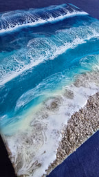 Handgefertigtes Resin-Meeresbild Solas Wild Tide (40 × 40 cm) auf einem strukturierten Gesso-Rahmen mit kraftvollen türkisblauen Wellen, natürlichem Sandstrand und schimmernden Perlmutt-Effekten.
