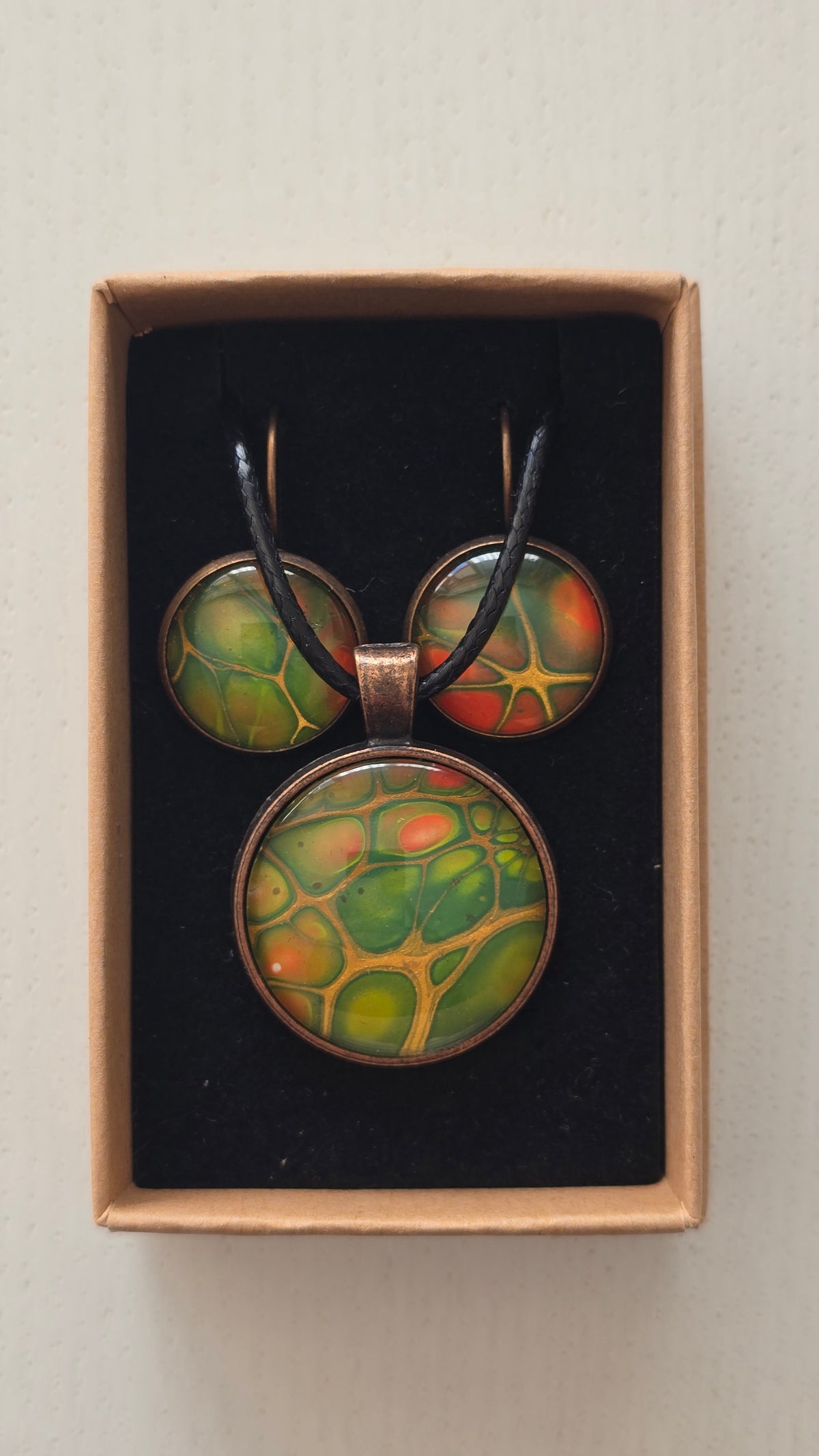 Rundes Cabochon-Schmuckset mit Kette und passenden Ohrringen in verschiedenen Grüntönen, mit orangefarbenen Akzenten und feinen kupferfarbenen Linien.