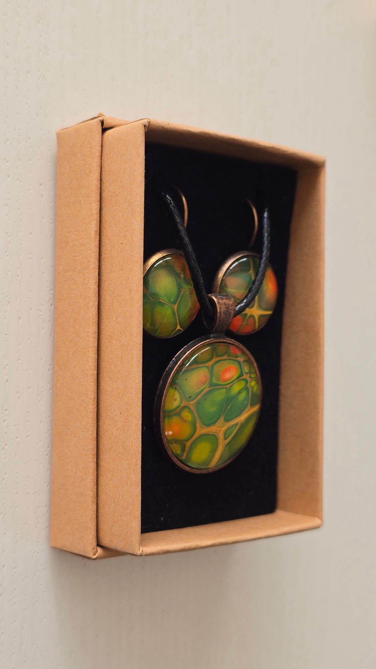 Rundes Cabochon-Schmuckset mit Kette und passenden Ohrringen in verschiedenen Grüntönen, mit orangefarbenen Akzenten und feinen kupferfarbenen Linien.